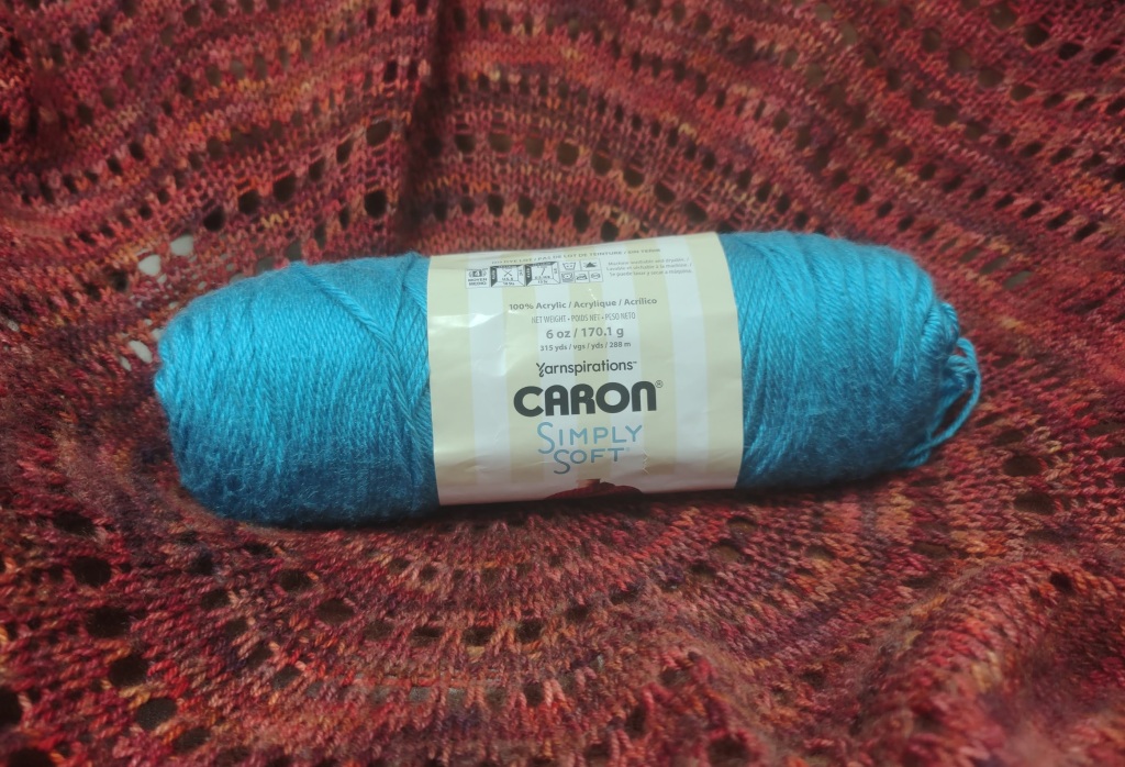 Bright turquoise yarn on a red knitted background